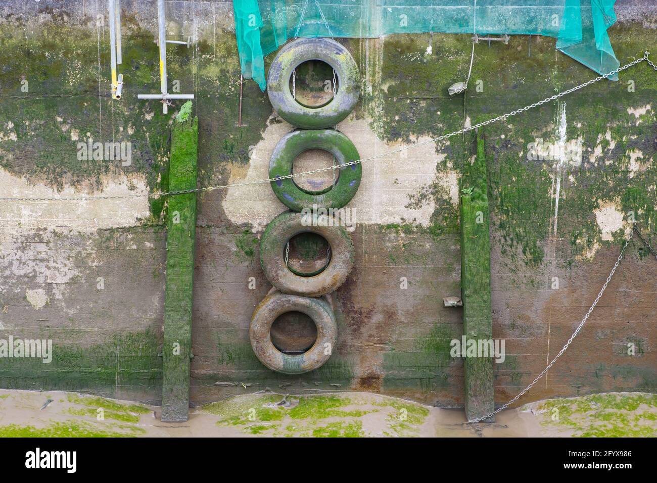 Car tyres on a brick wall with algae and river bed Stock Photo