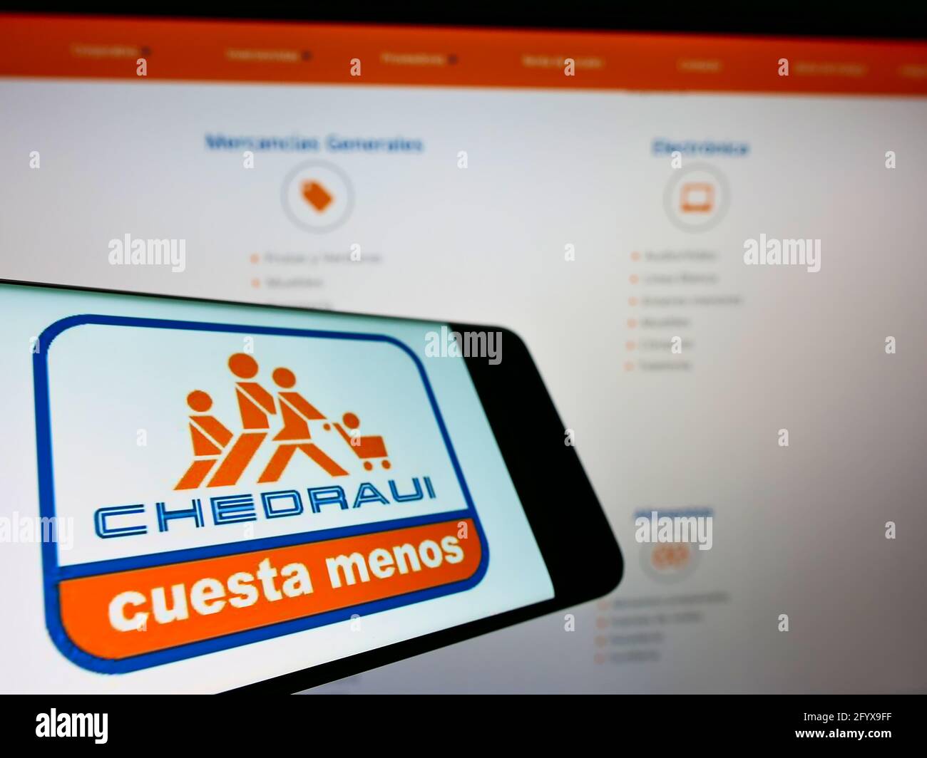 Smartphone with business logo of Mexican Grupo Comercial Chedraui S.A.B. de C.V. on screen in front of website. Focus on center of phone display. Stock Photo