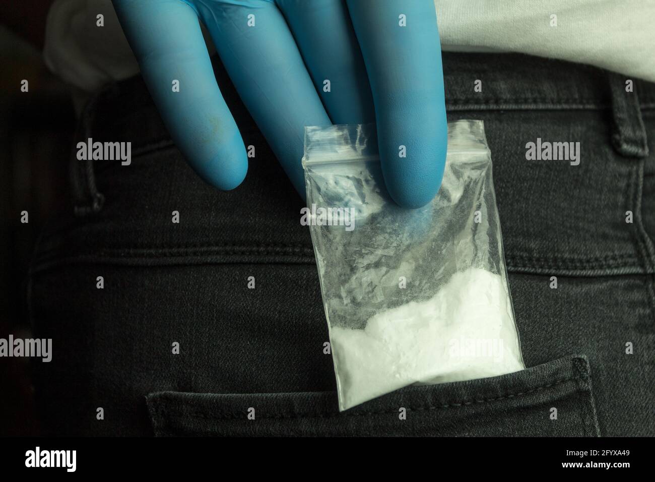 A drug bag in a jeans pocket. A package of drugs found in a pocket during a  police search. A hand takes drugs in a package from his pocket Stock Photo -