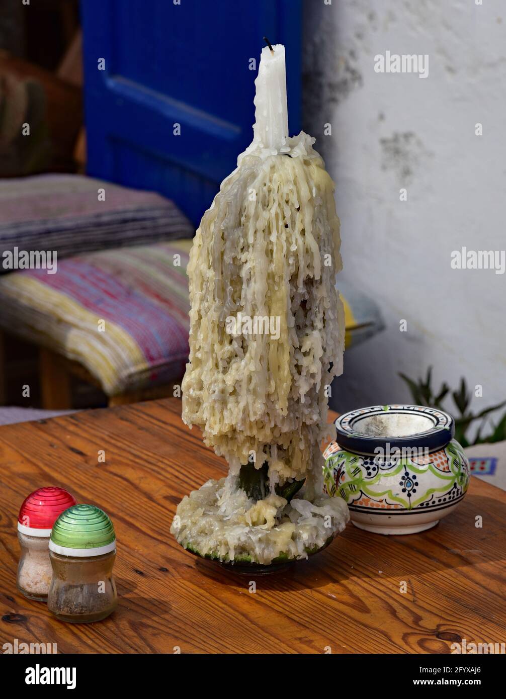 Multiple melted candles form stalactites of wax, on a table outside a restaurant in the Moroccan town of Essaouira, North Africa. Stock Photo