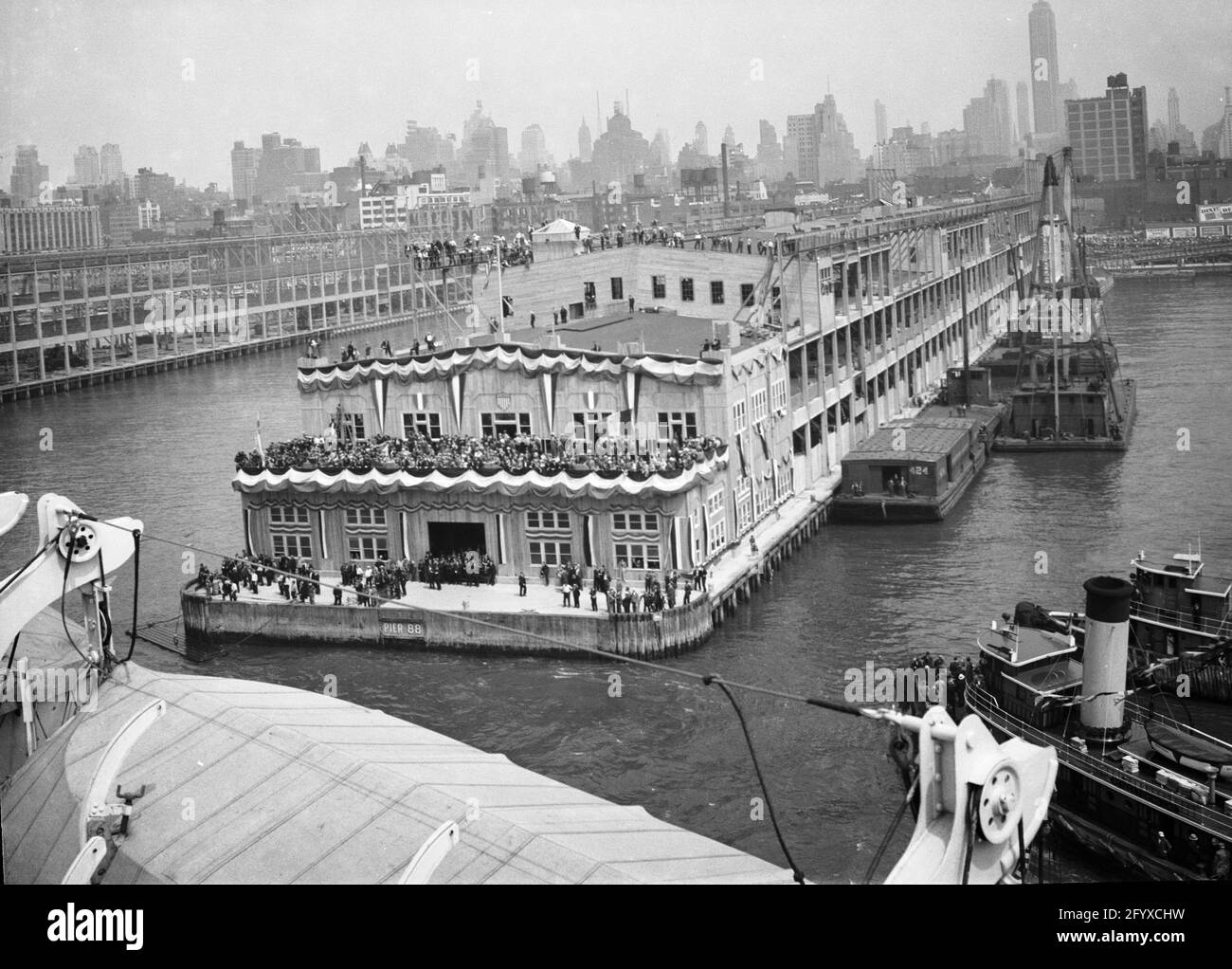 View from the SS Normandie of a band and large crowd at Pier 88 welcoming the ocean linerl upon its arrival, New York City, 1935. (Photo by Burton Holmes) Stock Photo