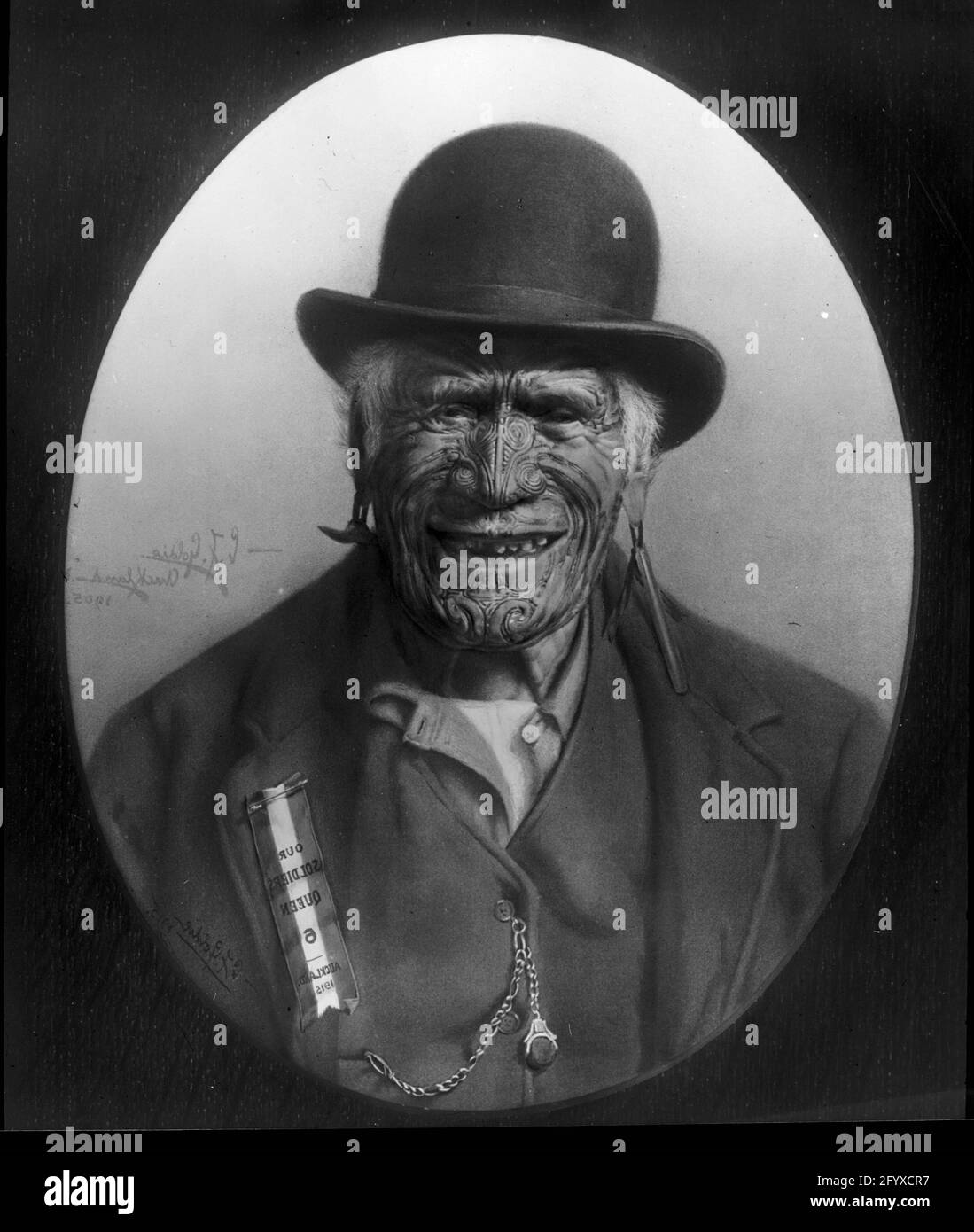 Portrait of Maori warrior and chief Te Aho-o-te-Rangi Wharepu (1811-1910) wearing a derby hat and ‘Our Soldiers Queen, Auckland 1915’ badge, Auckland, New Zealand, 1917. Originally photographed by Charles Goldie in 1905 and colorized by Burton Holmes in 1917. (Photo by Charles Goldie) Stock Photo