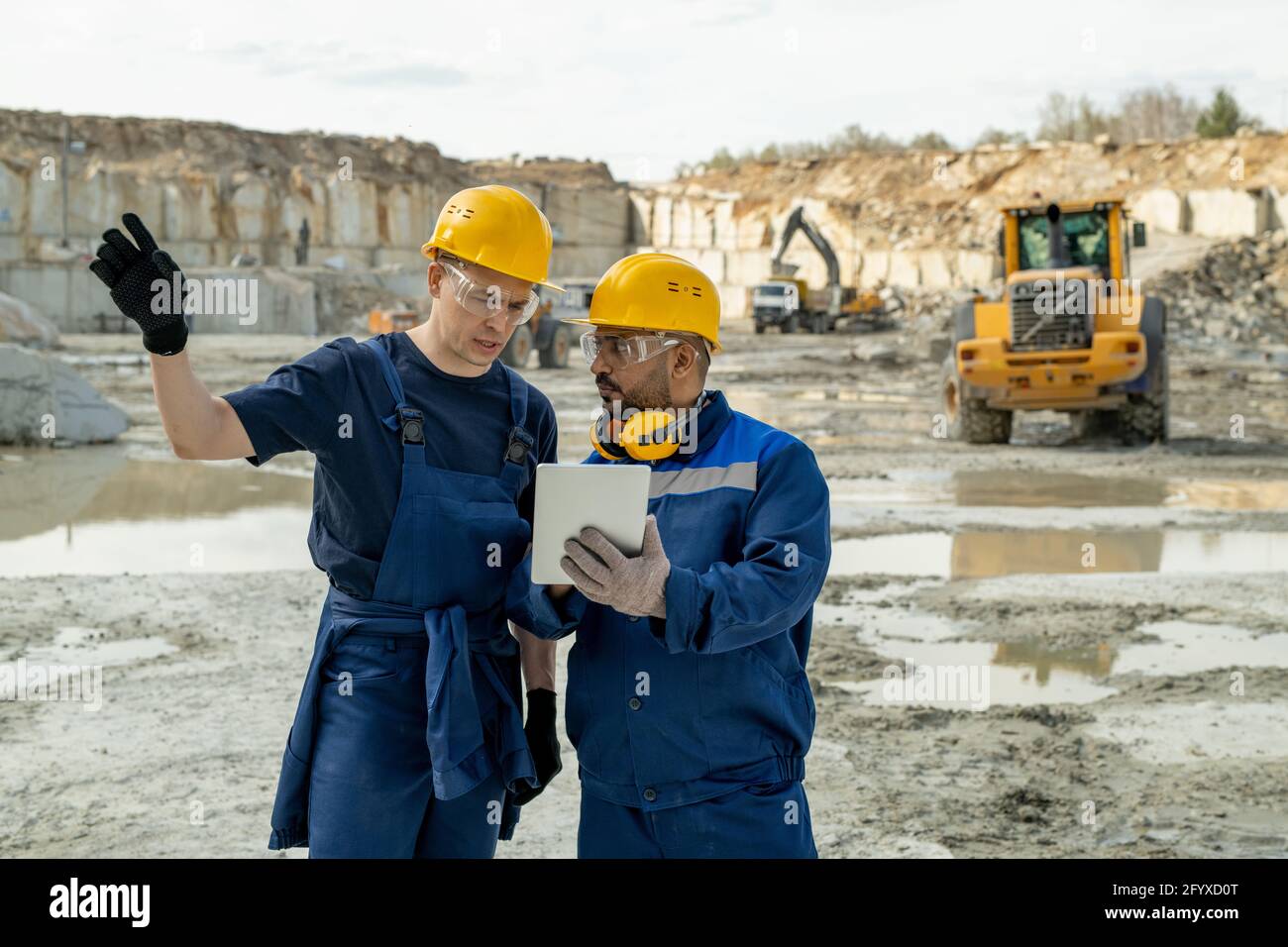 Contemporary builders discussing sketch in tablet during work Stock Photo