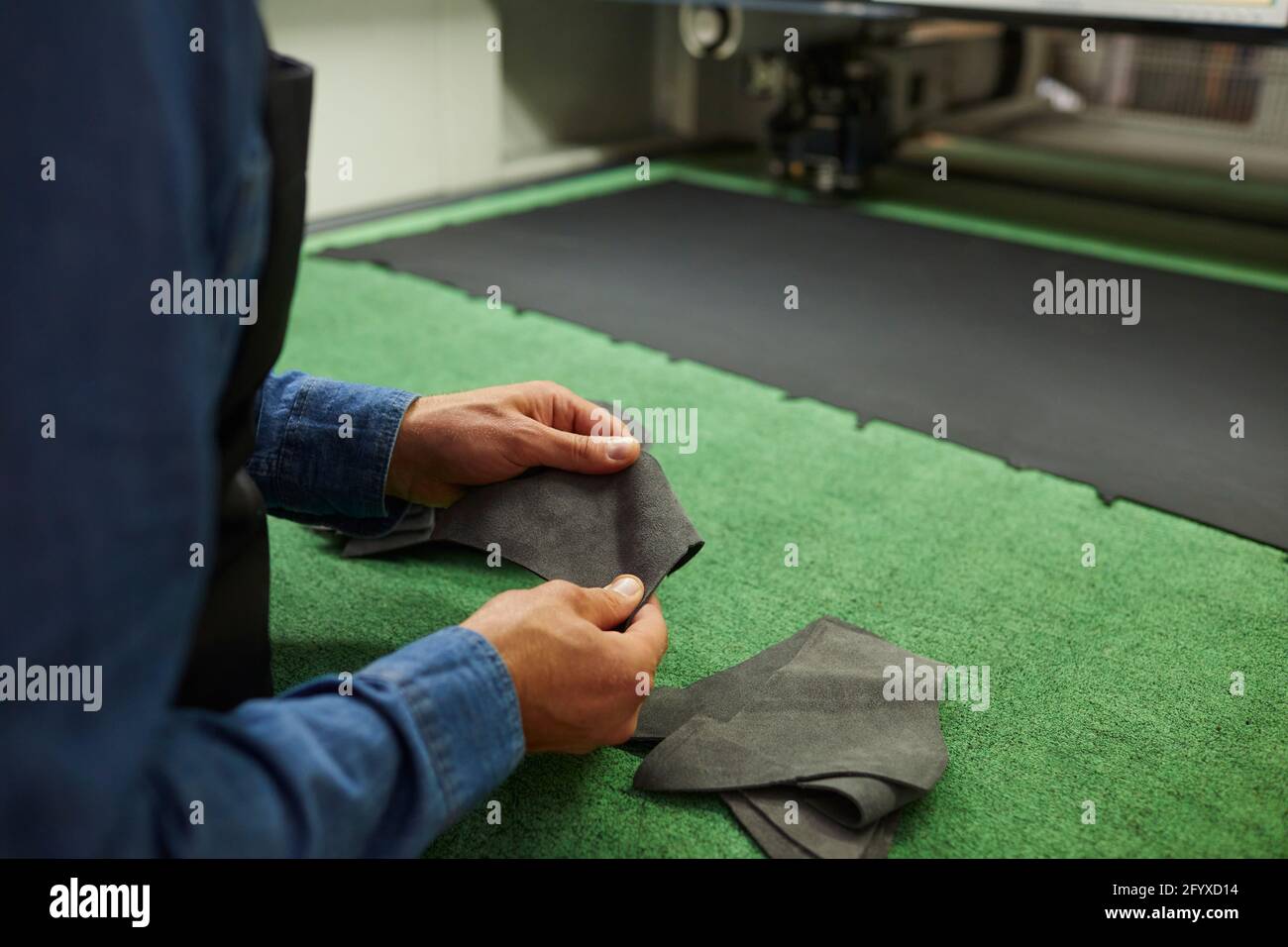Shoemaker hand cutting leather for shoe making skin patterns crop image Stock Photo