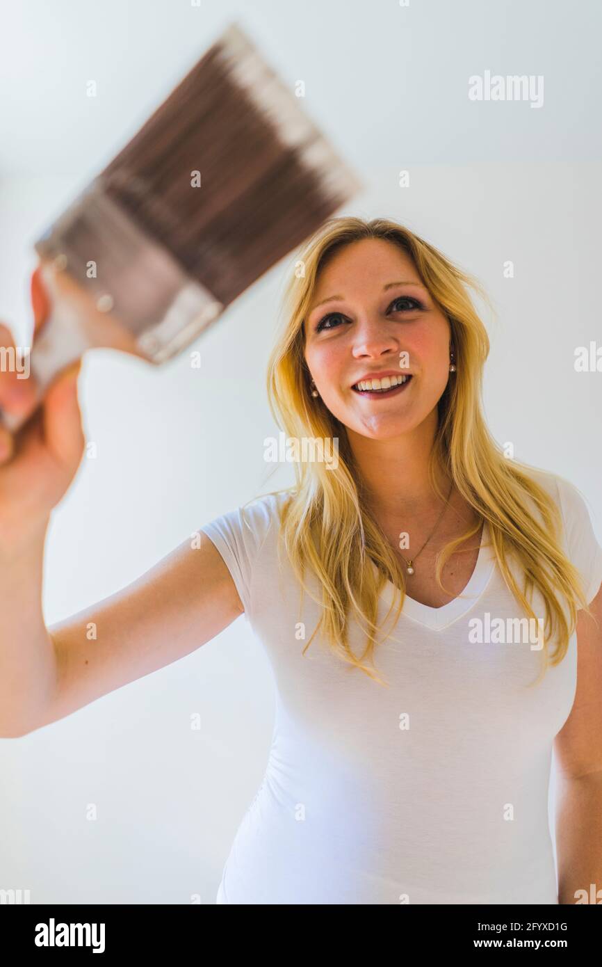 Beautiful blond pregnant woman standing in newly painted room during
