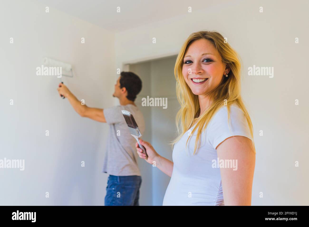 Young couple painting room in their new home during renovations Stock