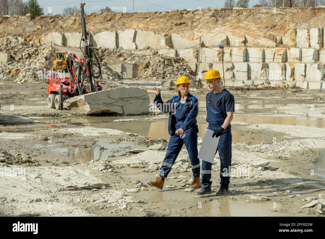 Two young builders discussing working points while walking down building place Stock Photo