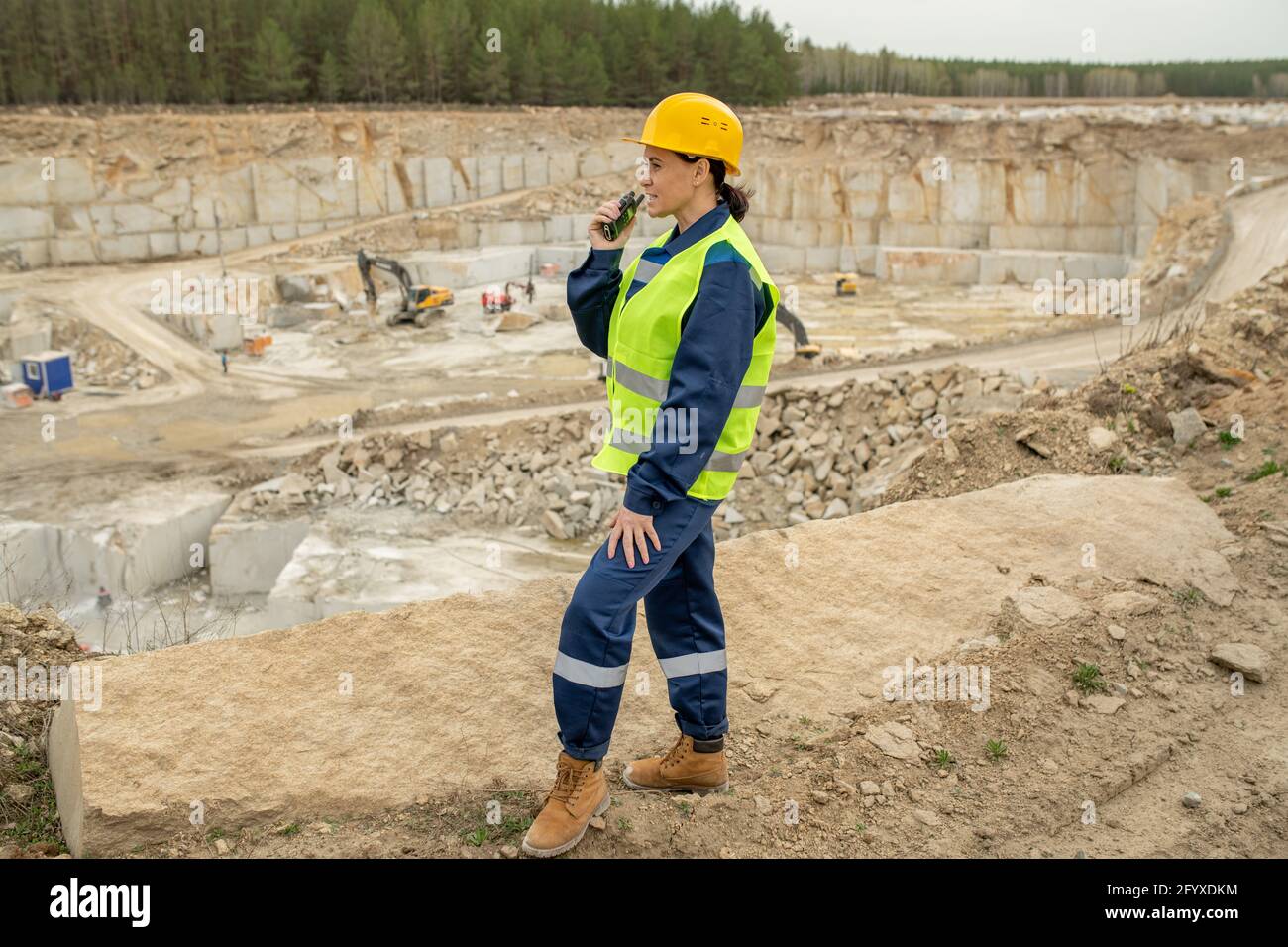 Female builder in uniform using walkie-talkie on construction site Stock Photo