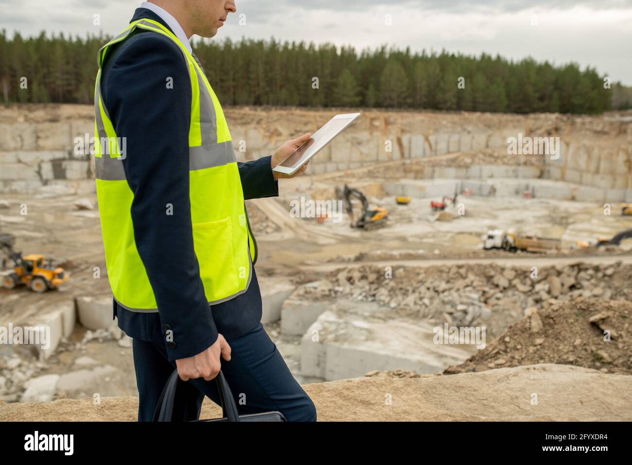 Contemporary architect in uniform using tablet while moving along construction site Stock Photo