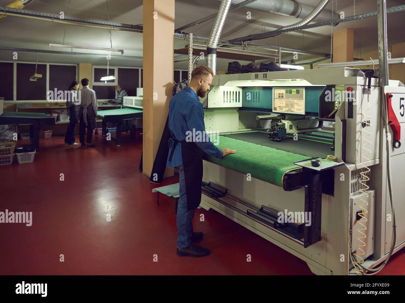 Worker using a cutting machine in a workshop of a footwear manufacturing factory Stock Photo