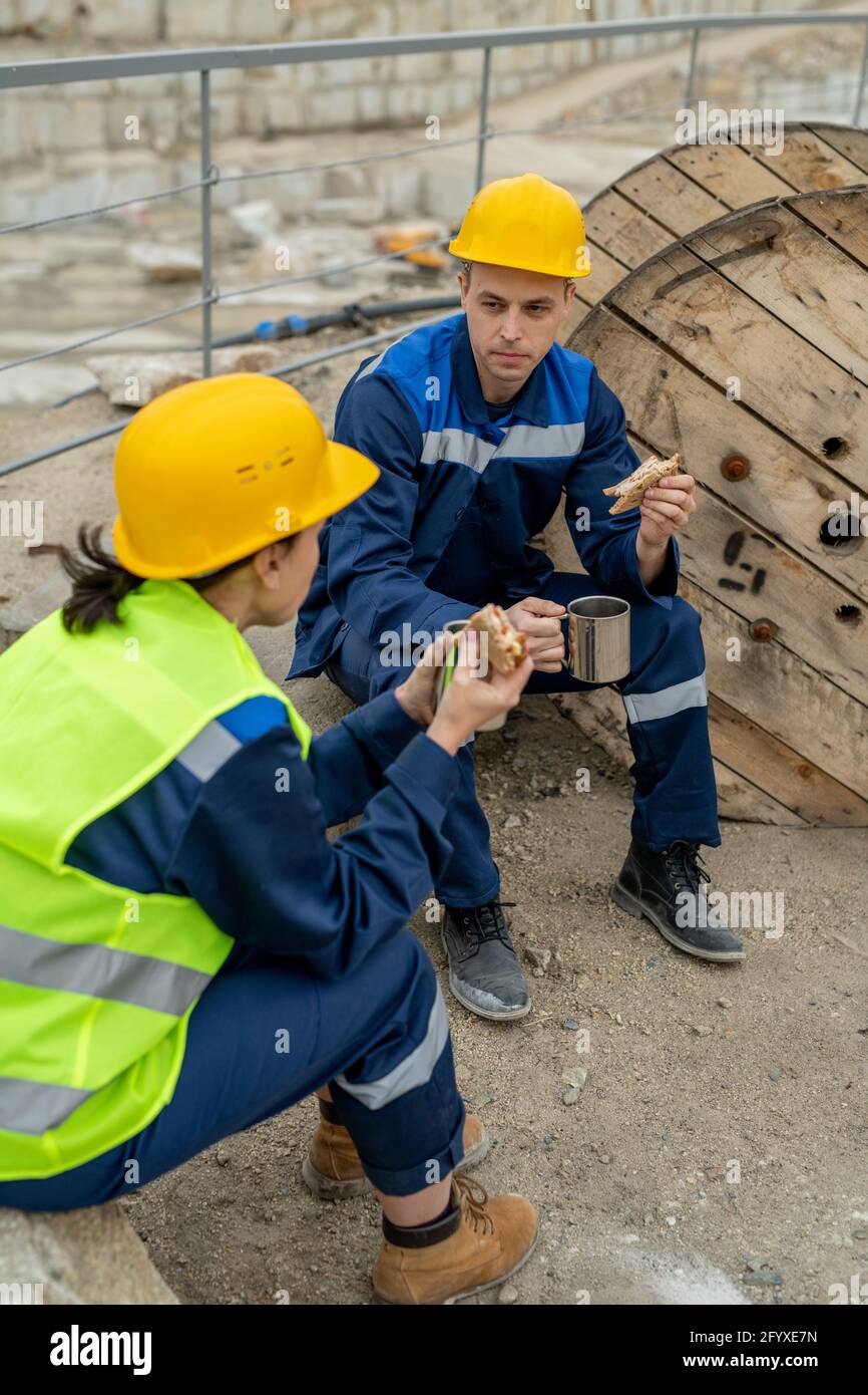 Two builders chatting and having lunch at break Stock Photo