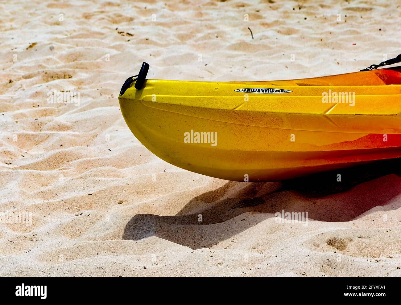 Banana shaped boat up on the beach at a Caribbean resort Stock Photo