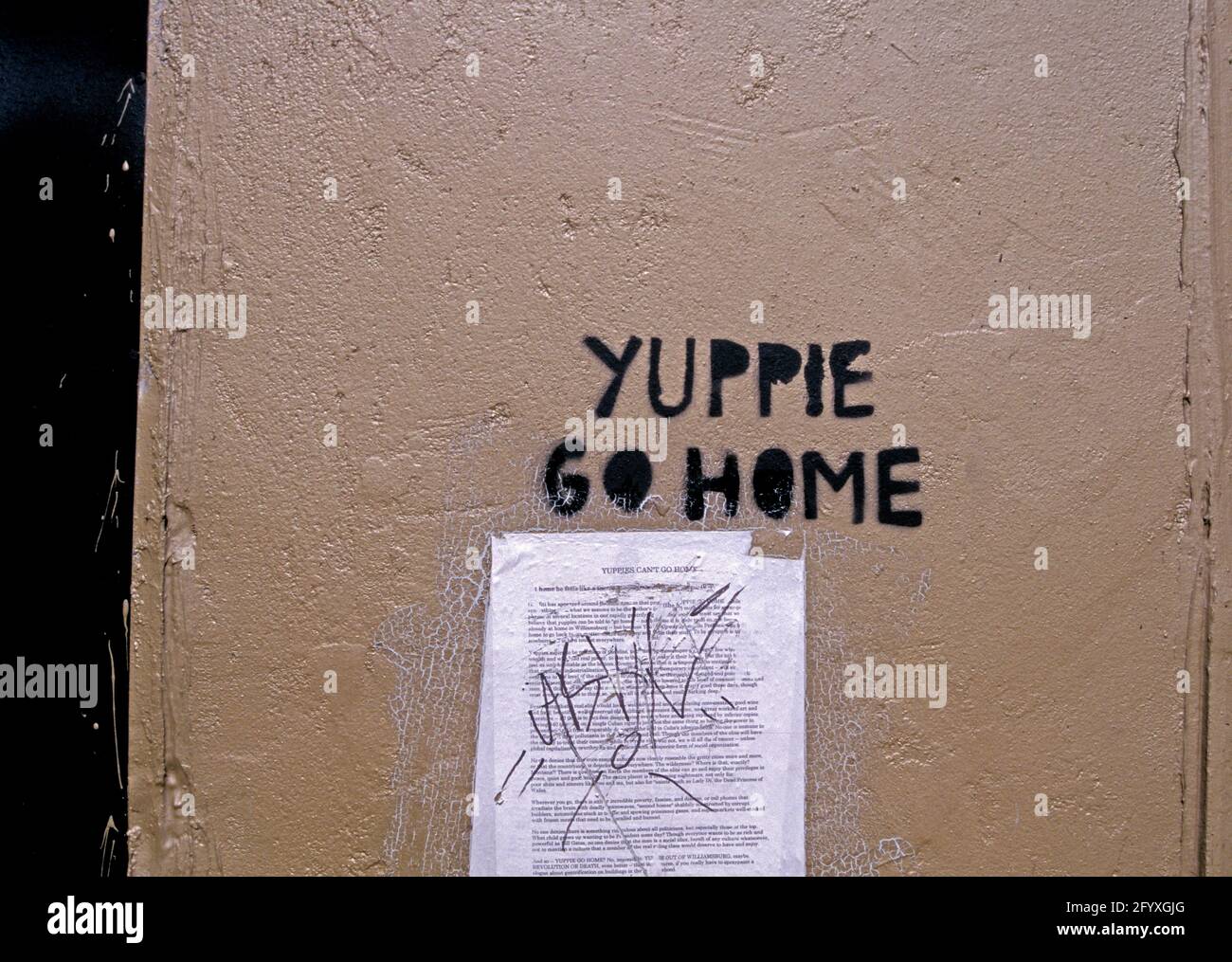 'Yuppie Go Home' sign on wall. Stock Photo