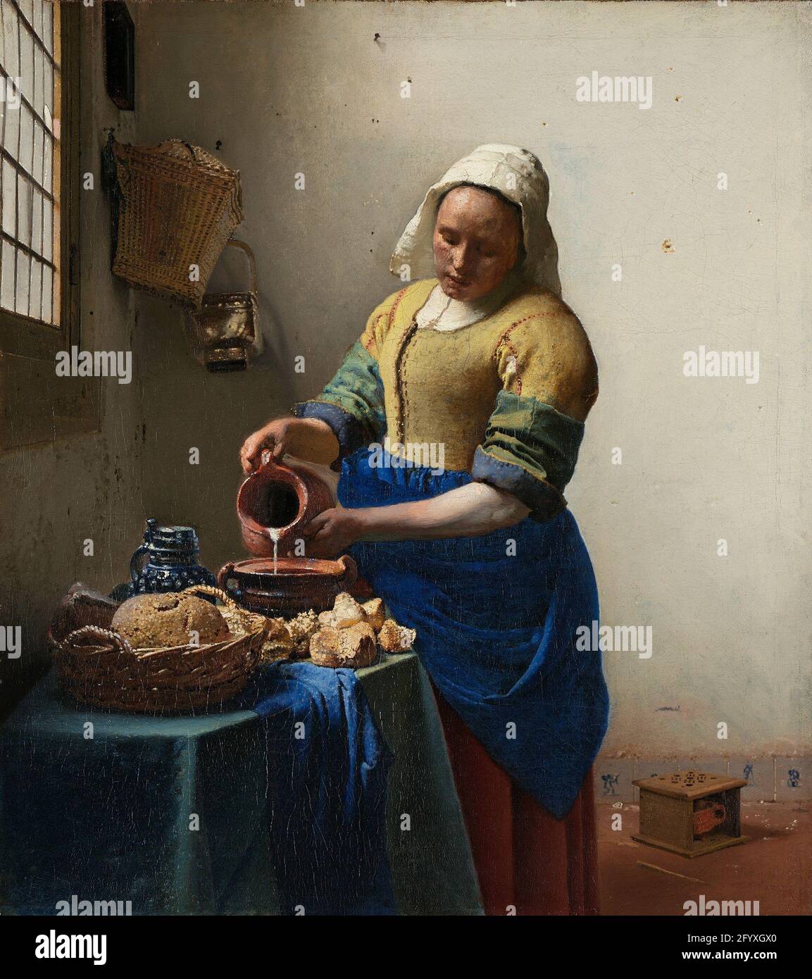 The Milkmaid. A maidservant pours milk, entirely absorbed in her work. Except for the stream of milk, everything else is still. Vermeer took this simple everyday activity and made it the subject of an impressive painting – the woman stands like a statue in the brightly lit room. Vermeer also had an eye for how light by means of hundreds of colourful dots plays over the surface of objects. Stock Photo