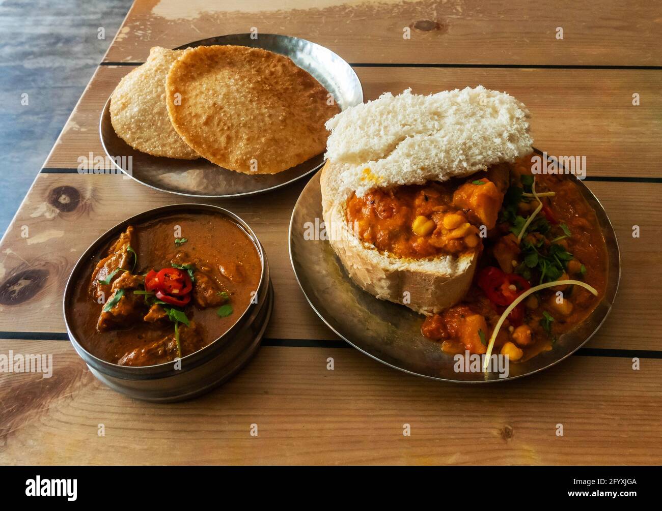 Mother Butter Chicken, Temple Dahl, and Puri on a rustic wooden table at Mowgli Indian Restaurant on Bold Street in Liverpool Stock Photo