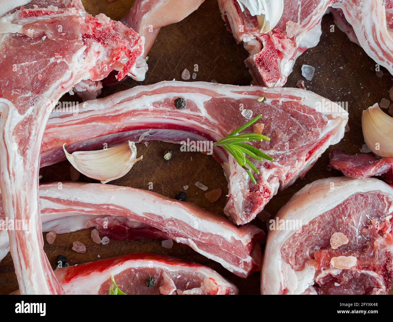 Raw lamb ribs with rosemary, garlic, salt and black pepper ready to be grilled Stock Photo