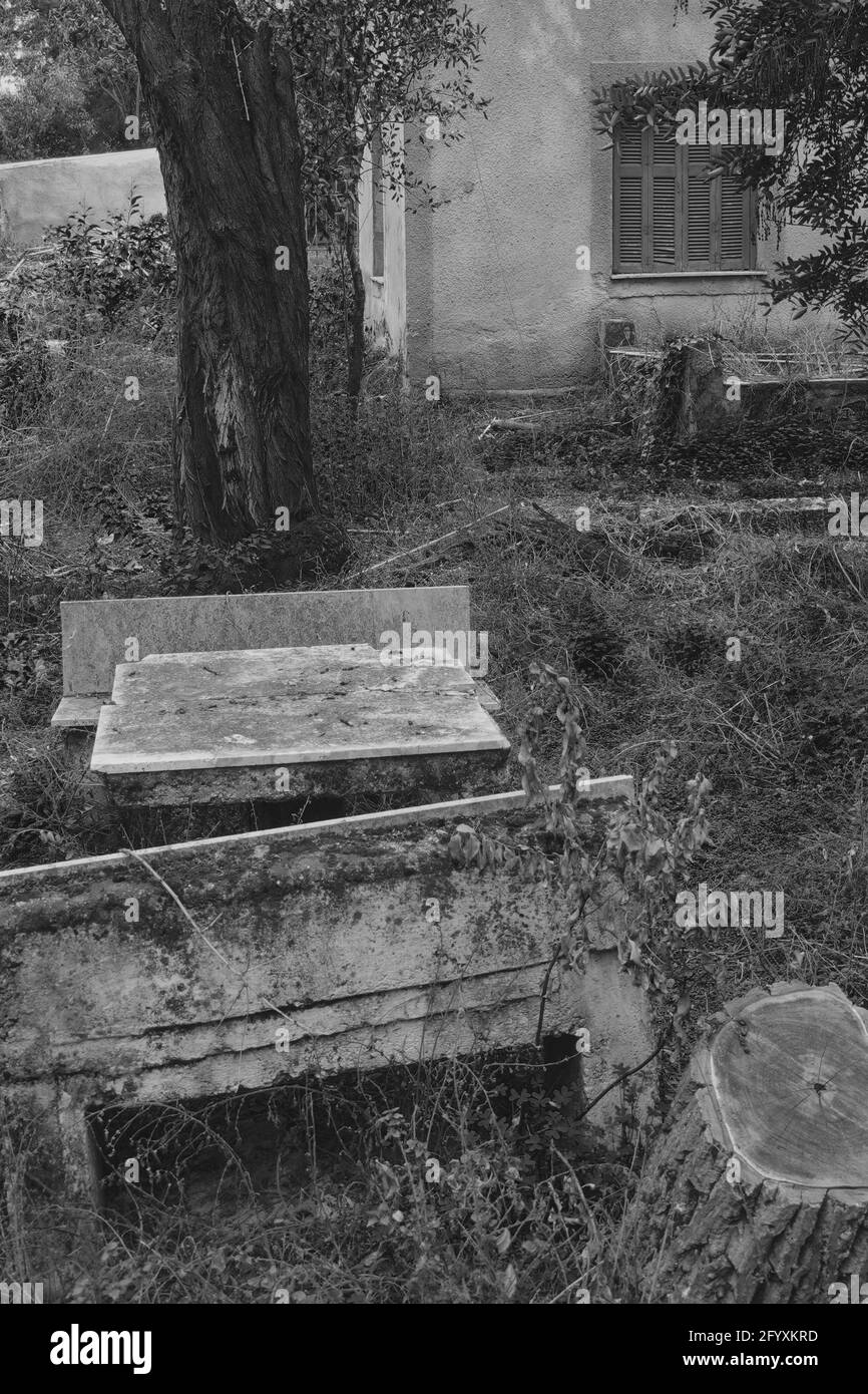 Old picnic table and benches on the yard of an abandoned house. Black and white. Stock Photo