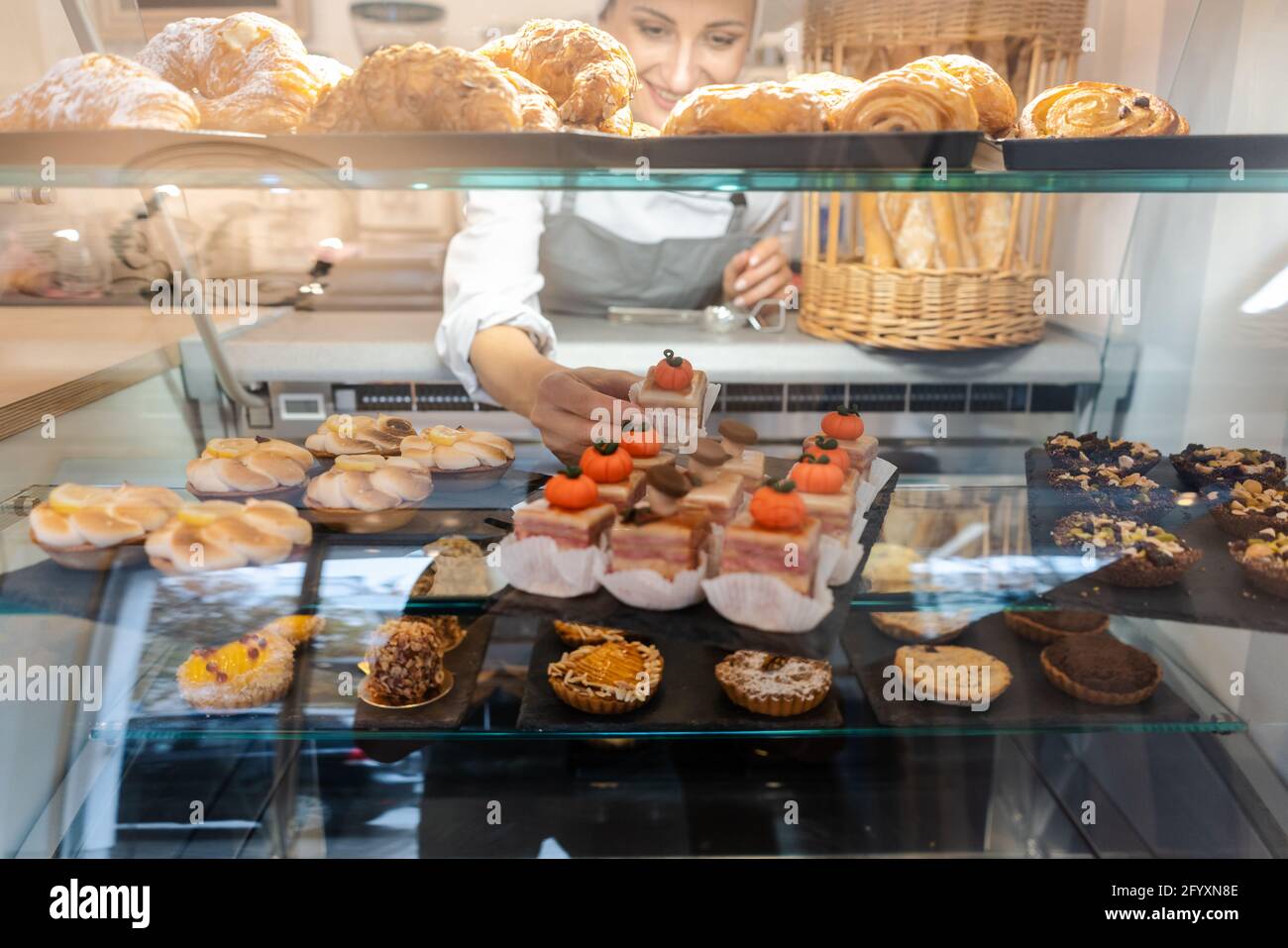 Confectioner shot through glass display in her shop Stock Photo