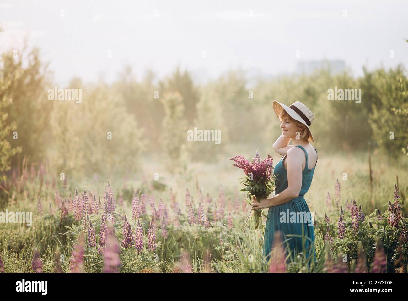 Beautiful romantic girl blonde in a dress and hat in a field with a ...