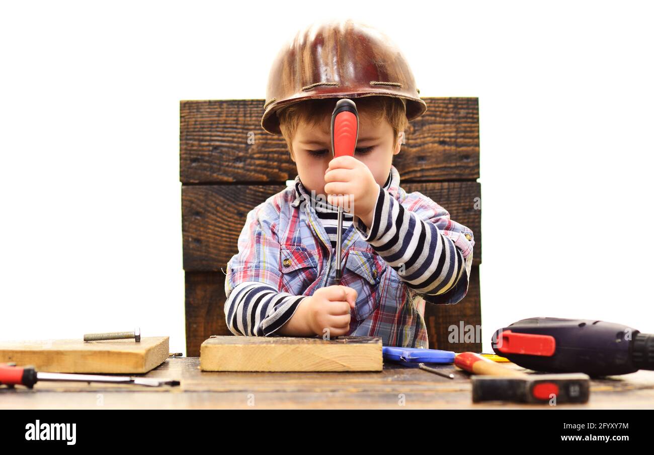 Kid twists bolt with screwdriver. Child Boy in workshop. Little Repairman. Repair tool. Stock Photo