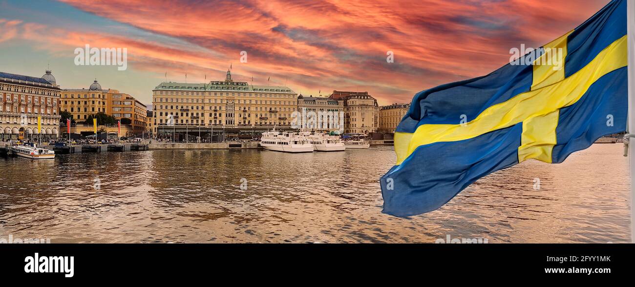 Golden hour panorama of historical Stockholm waterfront at sunset with national flag of Sweden on the first ground. Stock Photo