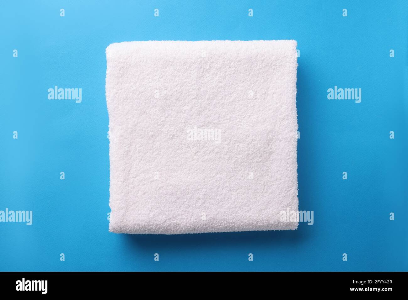 White terry towel is folded on blue background Stock Photo