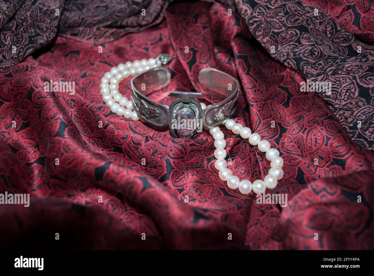 Pearl necklace vintage silver bracelet on dark cherry silk Stock Photo