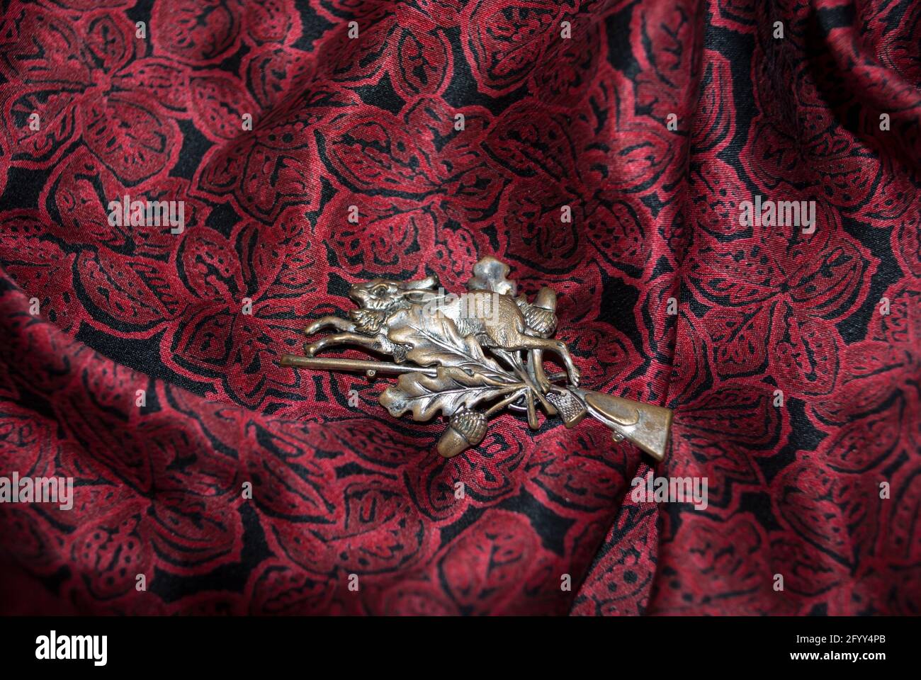 A silver rabbit vintage brooch on dark cherry silk. Stock Photo