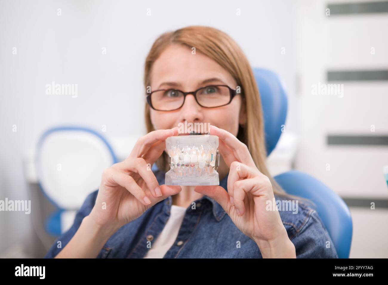 Female patient holding dental model with braces, waiting for medical