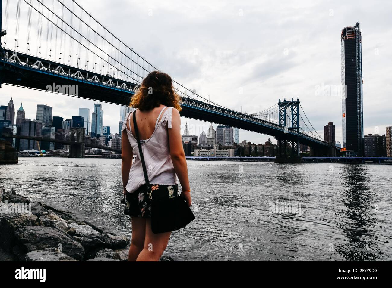 A back view of a young female looking at the skyline of the city in ...