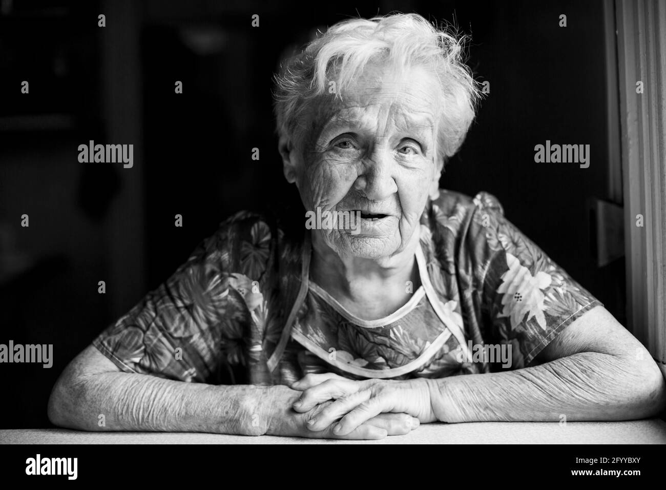 Portrait of an old woman sitting in her home. Black and white photo ...