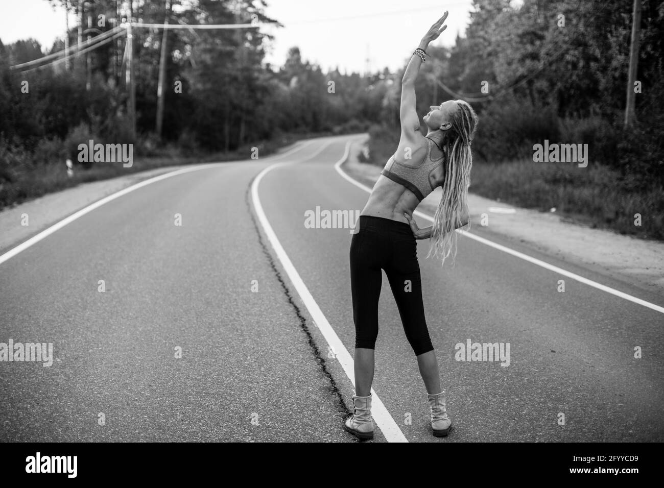 Woman warm-up before jogging on the road. Black and white photo. Stock Photo
