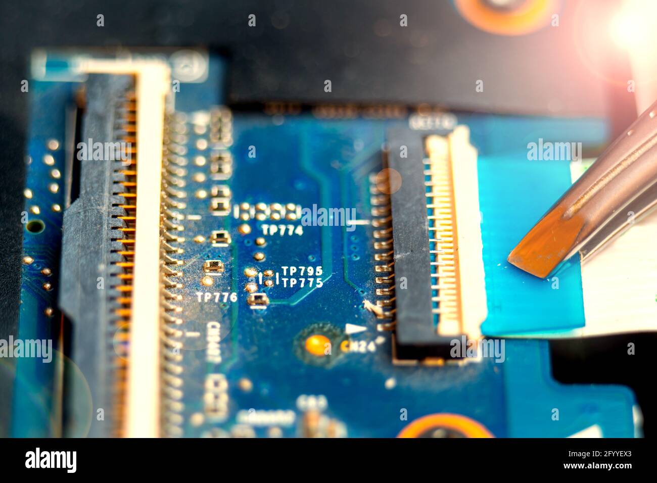 Connecting a flex cable to the laptop motherboard with tweezers, laptop repair in a service center Stock Photo