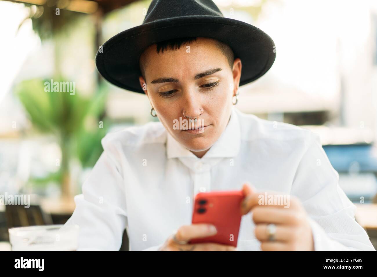 Serious Masculine Woman Wearing White Shirt And Hat With Mobile Phone Sitting In Cafe Stock 6877