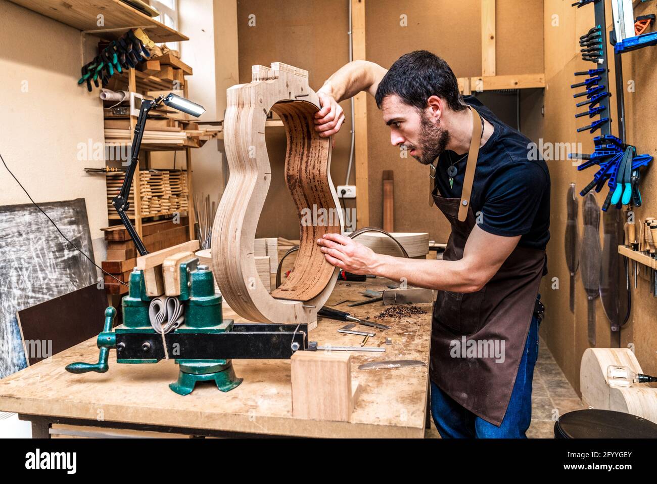 Adult male artisan making classical musical instrument with wooden ...