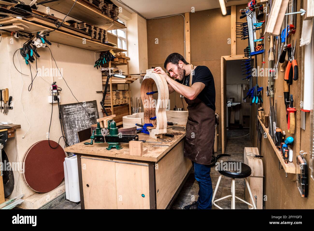 Adult male artisan making classical musical instrument with wooden ...
