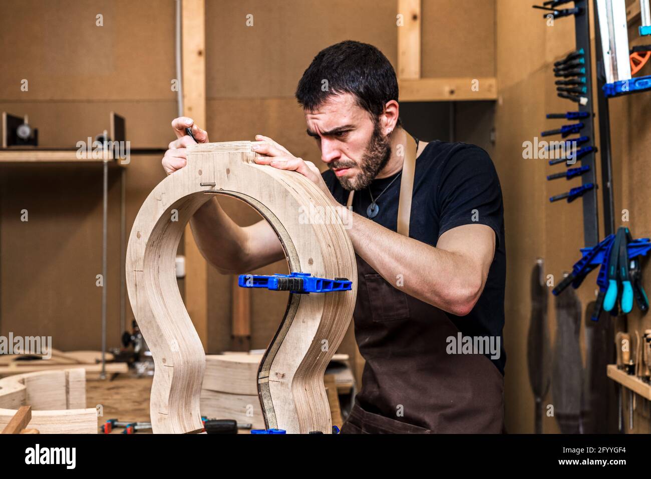 Adult male artisan making classical musical instrument with wooden ...