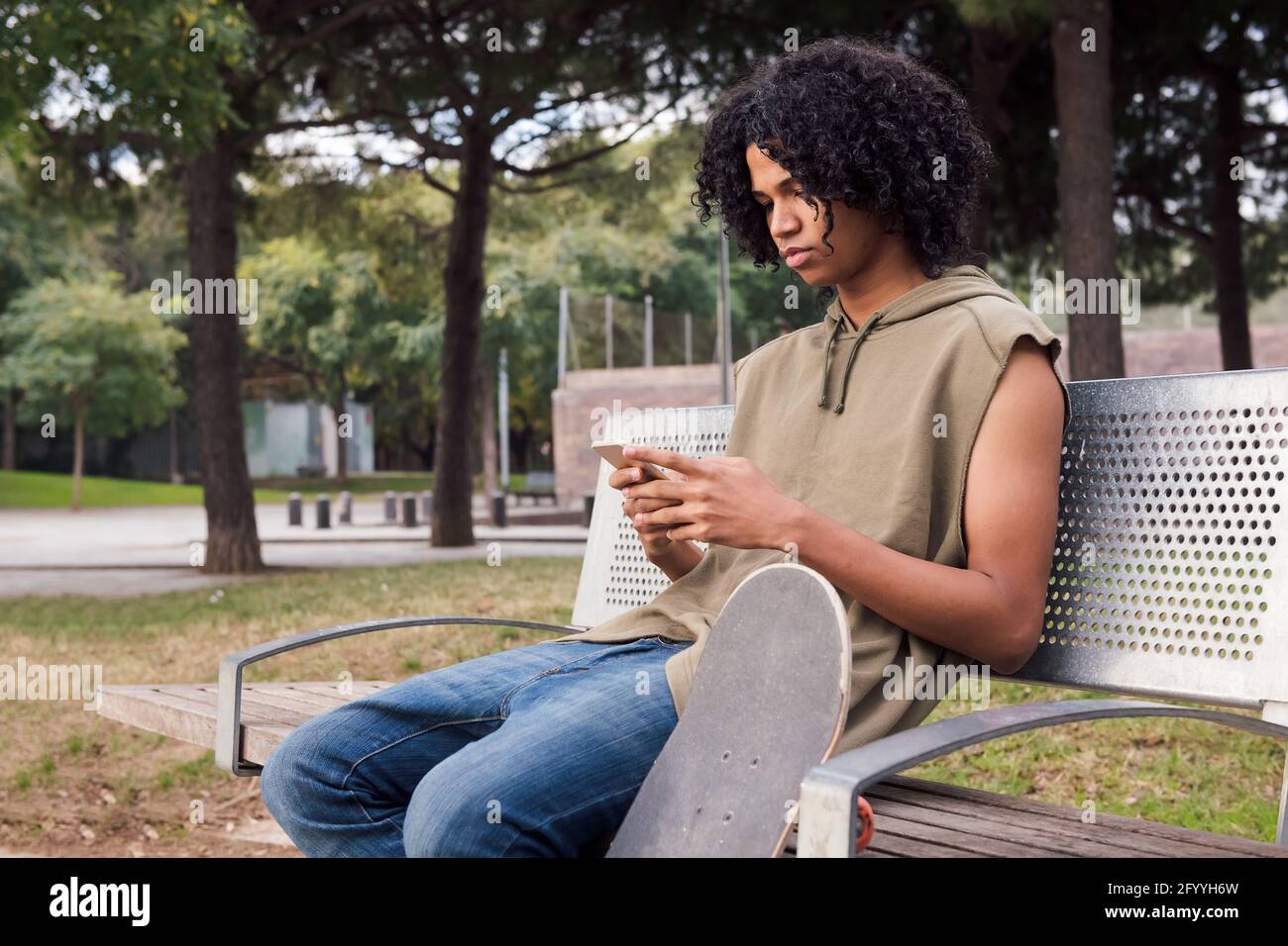 Serious African American curly haired male texting message on mobile ...