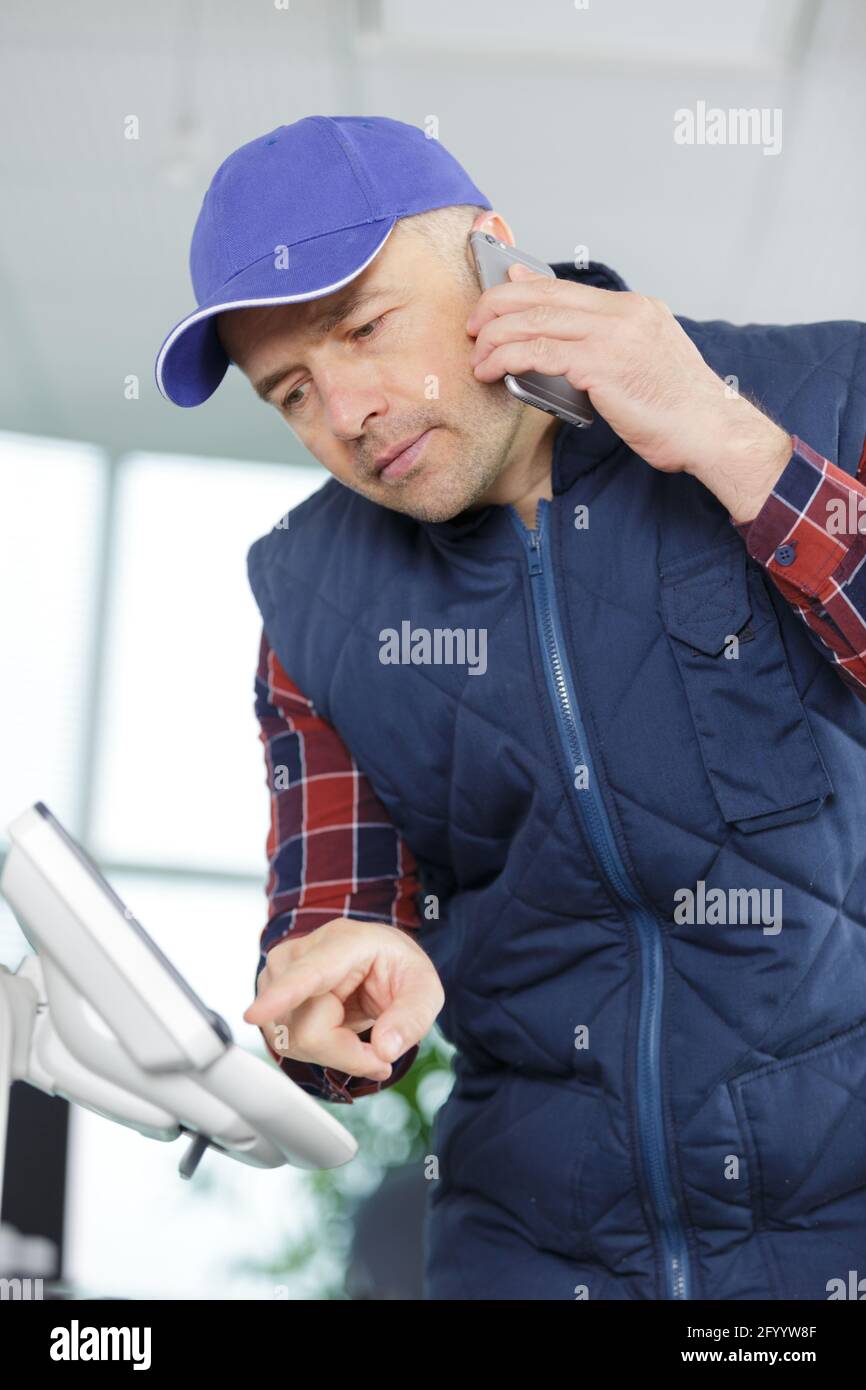 engineer on smartphone setting up the photocopier machine Stock Photo