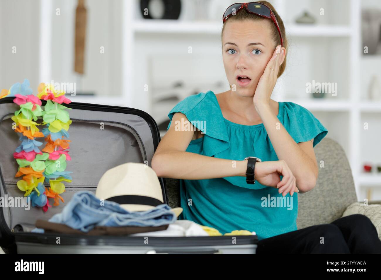 woman packing suitcase panicking as she realises the time Stock Photo