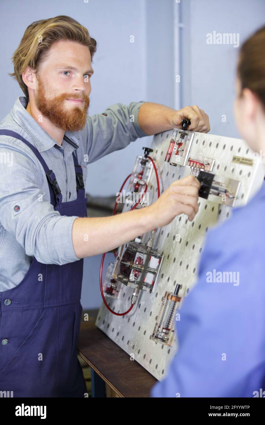 engineer and apprentice examining component in factory Stock Photo