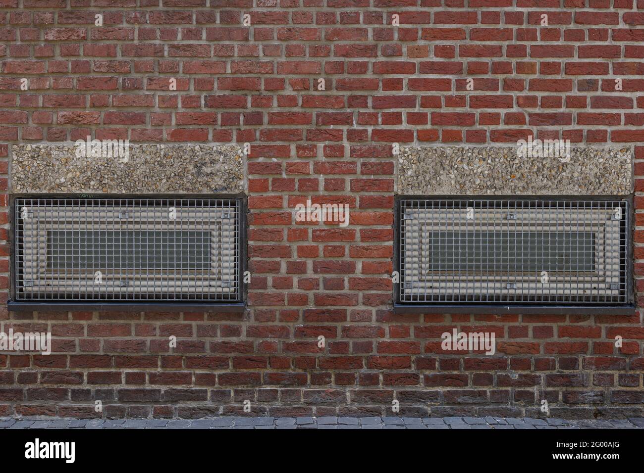 Exterior of metal rectangular windows with grating on rough brick wall. Stock Photo