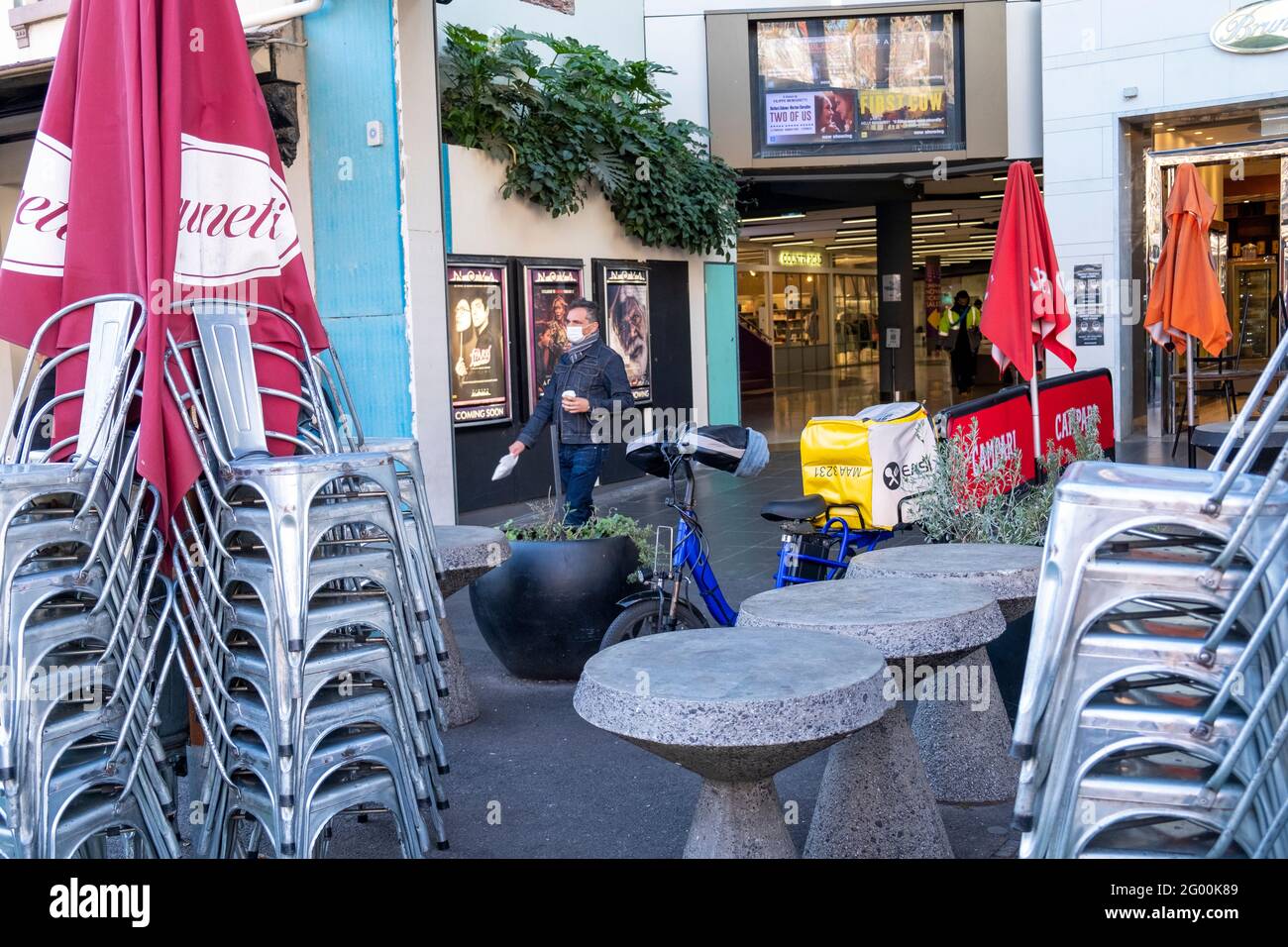 A man carries his coffee through an outdoor bar which has been closed because of the latest coronavirus lockdown in Melbourne, Australia. Stock Photo