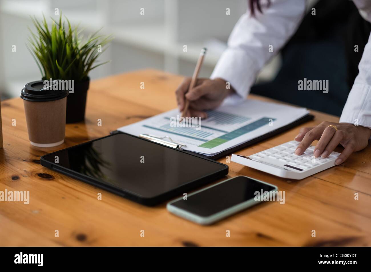 Businesswoman inspecting and checking the business reports graphs to audit the financial reports by calculating the results. Analyzing the revenue and Stock Photo