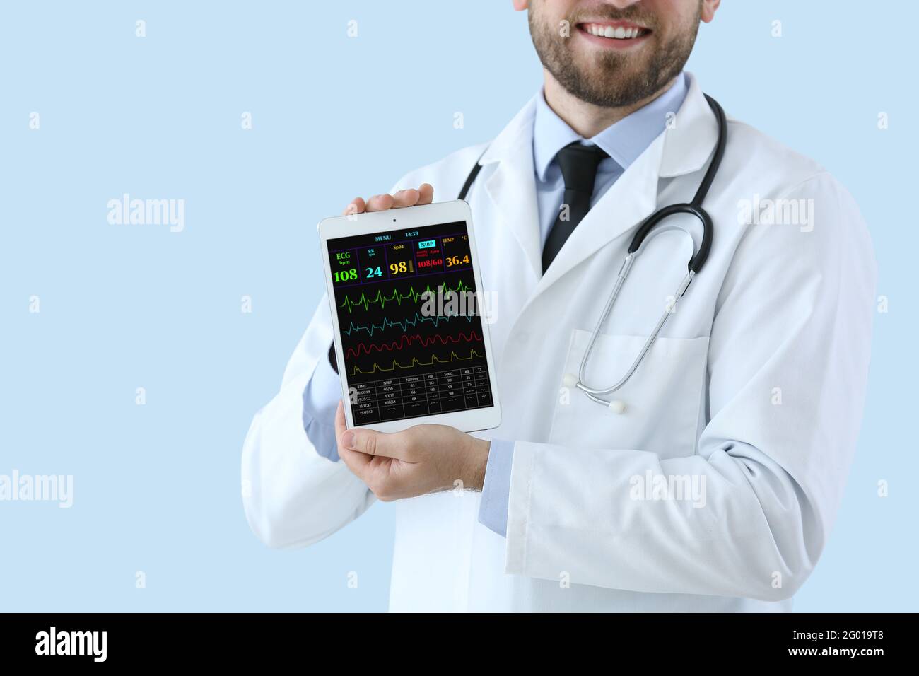 Male doctor with heart rate monitor on screen of tablet computer ...
