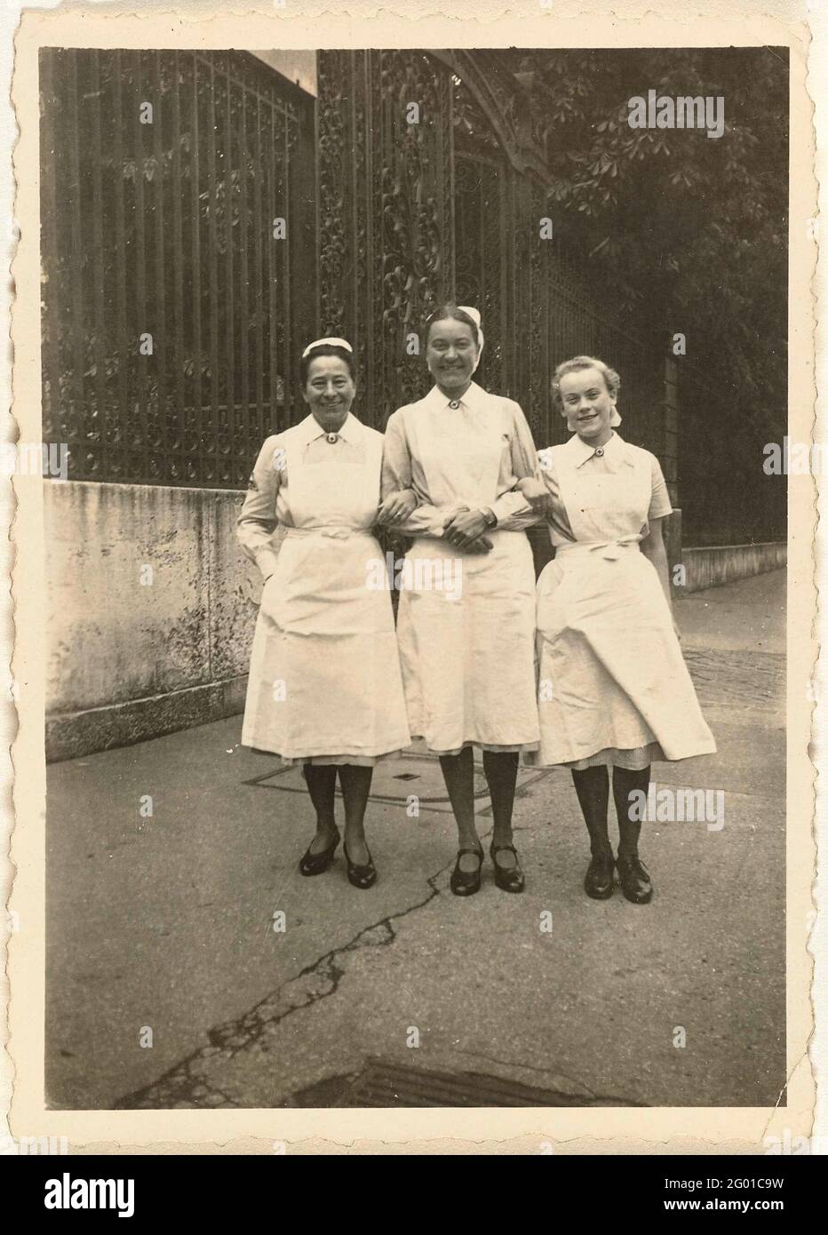 Three nurses. Three nurses in uniform, a fence on the left. In Paris at the beginning of May 1943. Part of the group loose photos associated with the photo album over the Kriegsmarine 1940-1943. Stock Photo