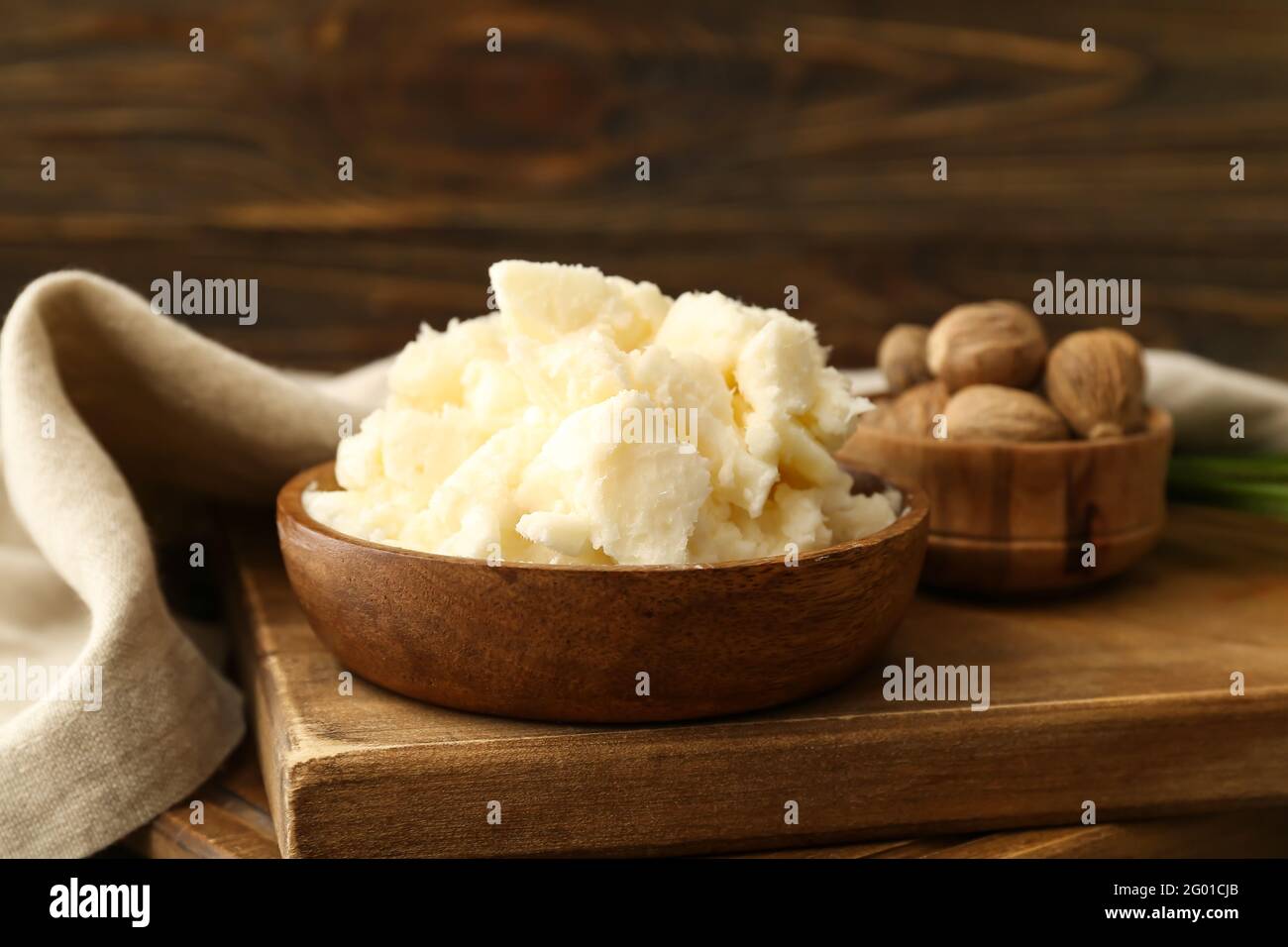Bowls with shea butter and nuts on wooden background, closeup Stock ...