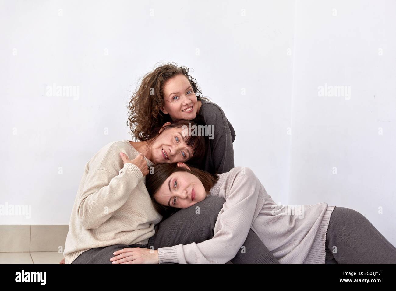 Content mature mother hugging adult daughters on white background in