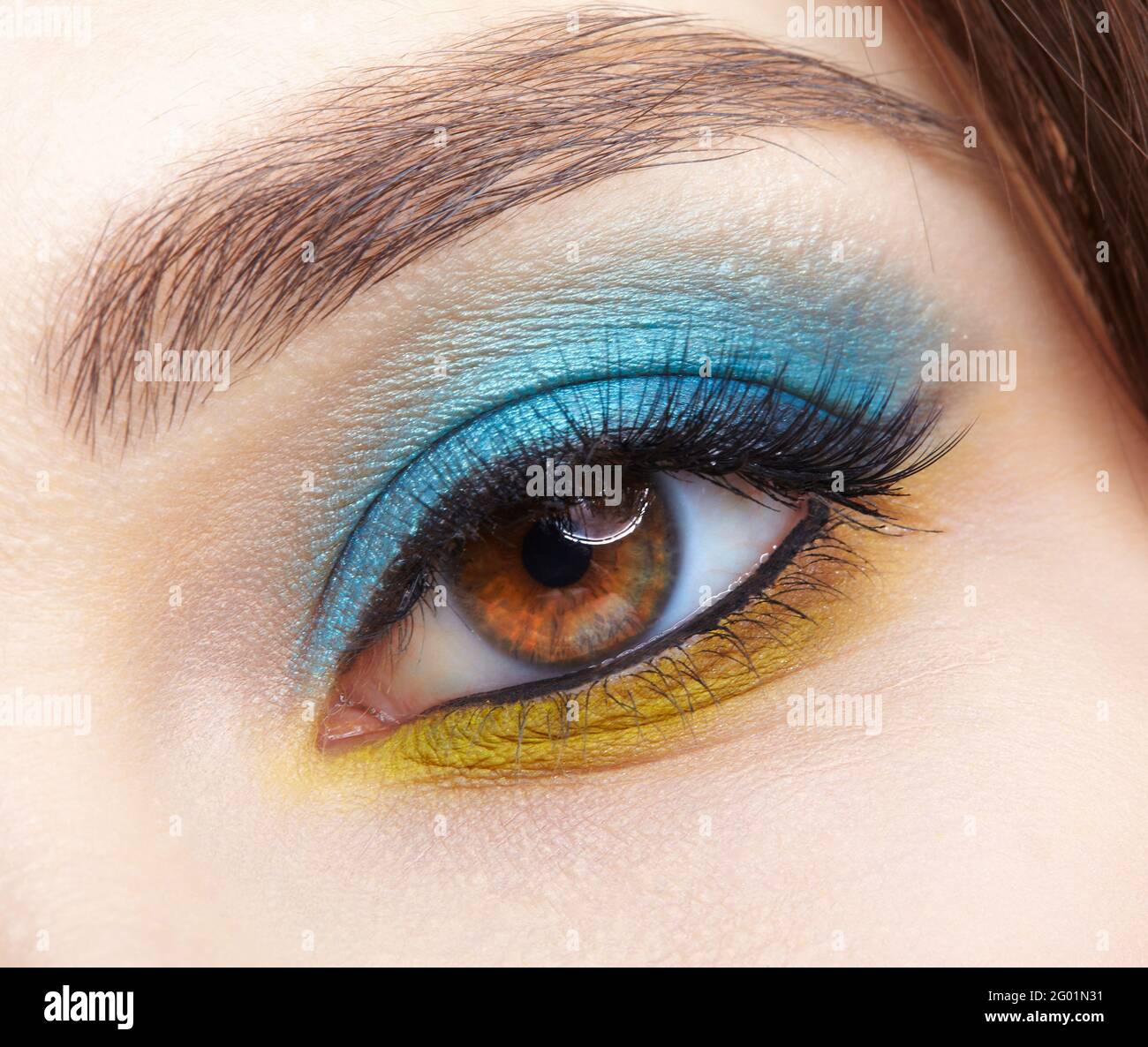 Closeup macro shot of human female eye. Woman with natural evening vogue eyes beauty makeup. Eye with blue smoky eyes shadows and yellow liner. Stock Photo