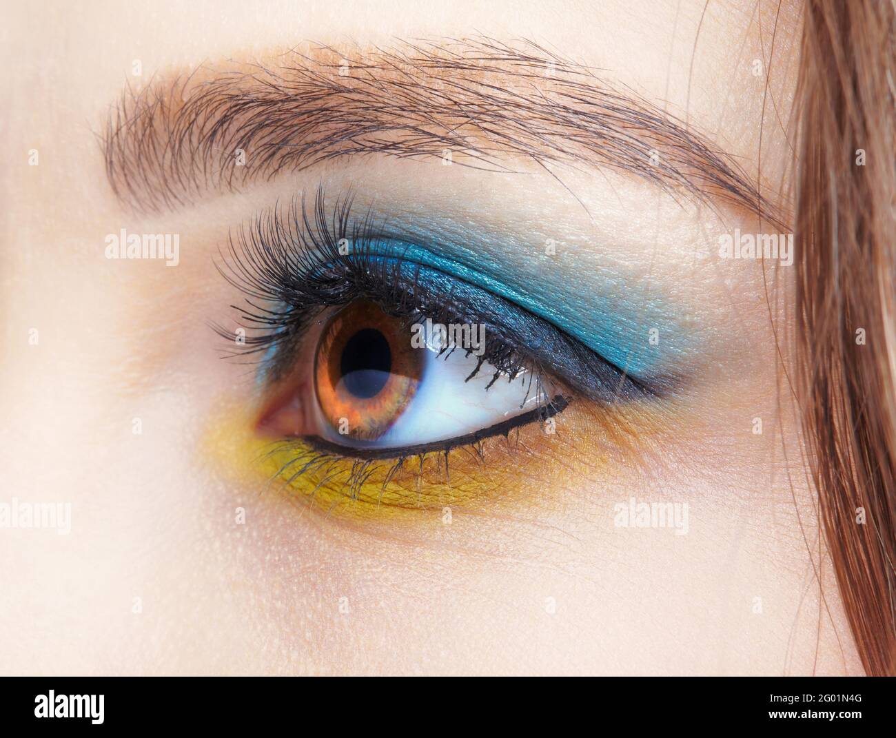 Closeup macro shot of human female eye. Woman with natural evening vogue eyes beauty makeup. Eye with blue smoky eyes shadows and yellow liner. Stock Photo
